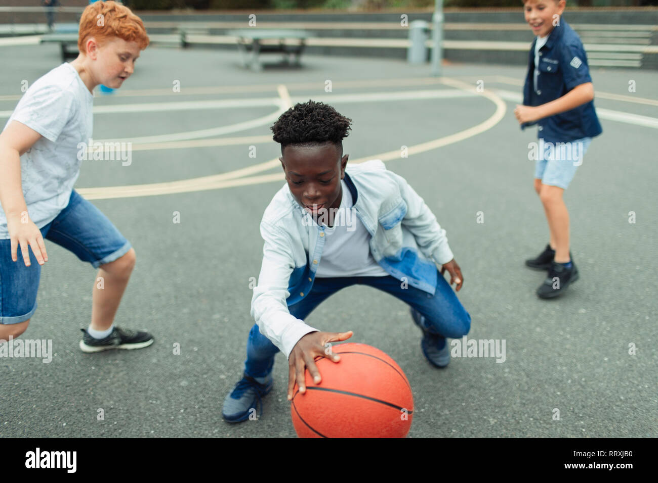 Le Tween garçons jouant au basket-ball dans la cour de l'école Banque D'Images