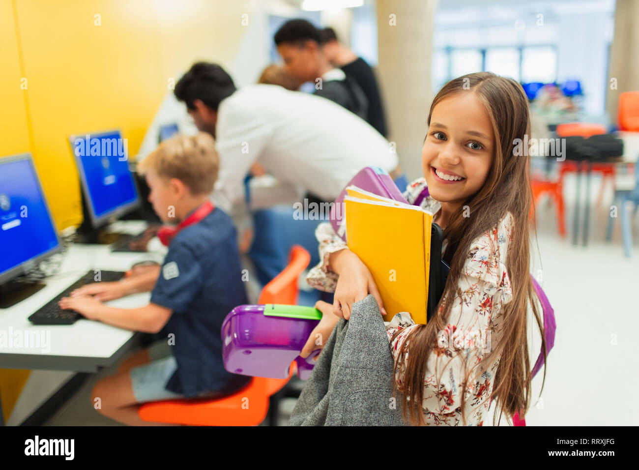 Portrait souriant, confiant junior high girl student portant des livres dans la bibliothèque Banque D'Images