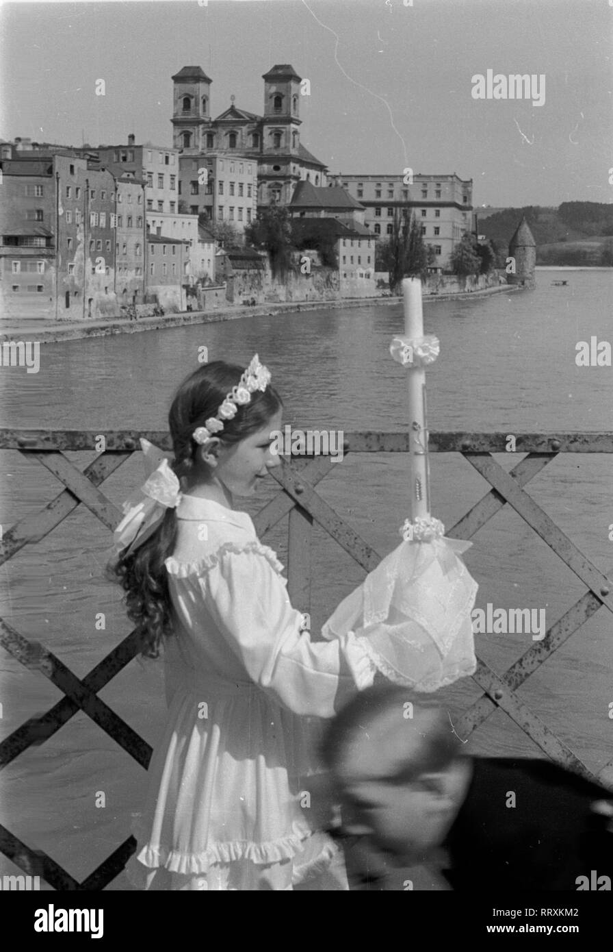 Allemagne - Süddeutschland ca. 1950er, Passau, Mädchen mit Kerze am Fluss. Jeune fille à sa Première Communion, années 1950. Banque D'Images
