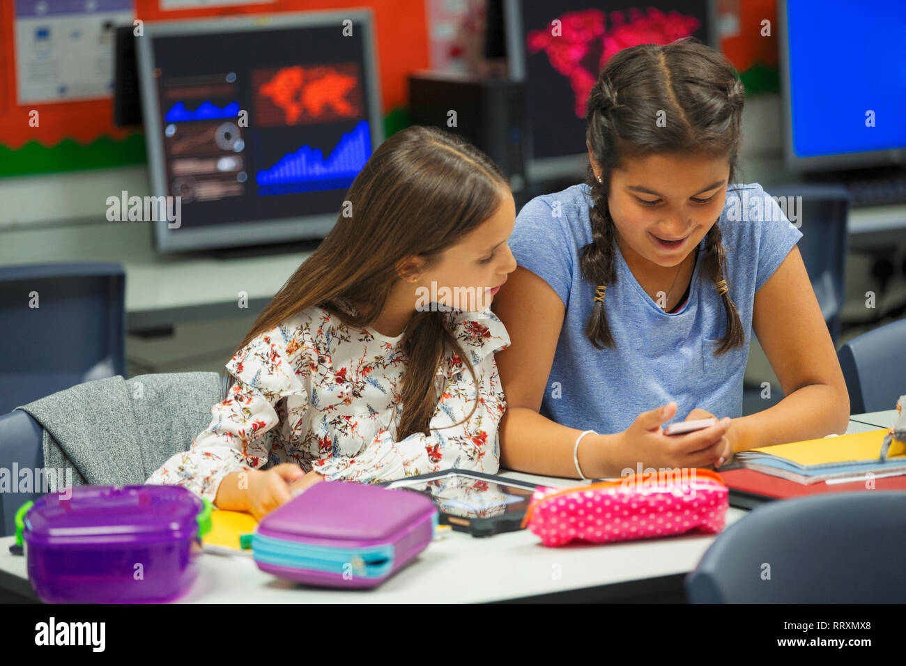 Junior High school girl élèves à l'aide de smart phone at desk in classroom Banque D'Images