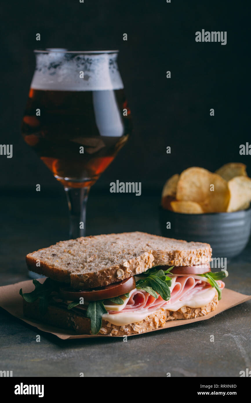 Délicieux sandwich au jambon, fromage, laitue et tomates avec un verre de bière et des frites et dark grunge background Banque D'Images