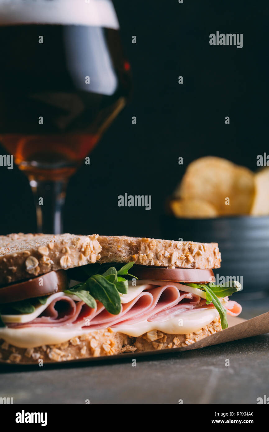 Délicieux sandwich au jambon, fromage, laitue et tomates avec un verre de bière et des frites et dark grunge background Banque D'Images