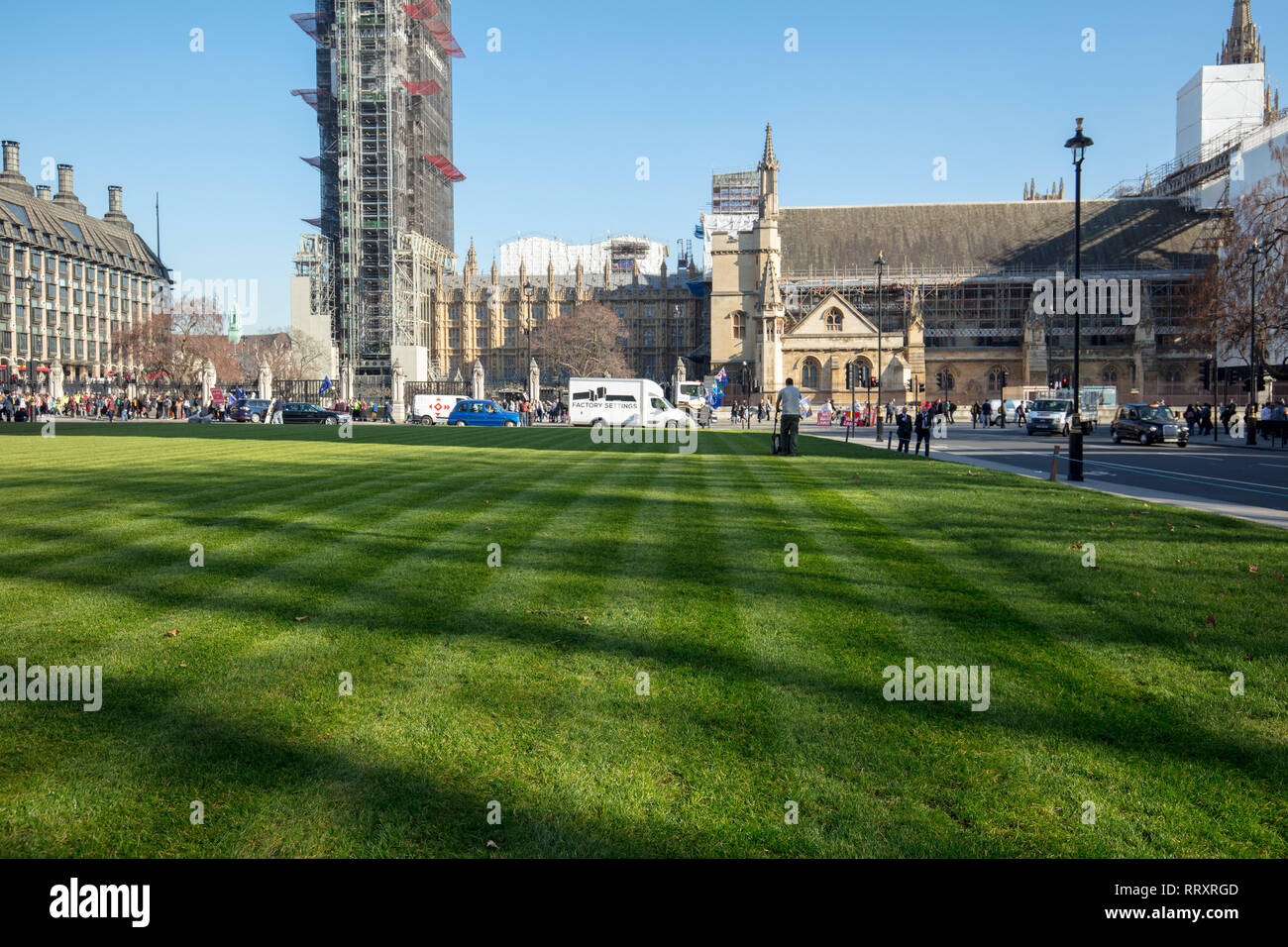 Après le renouvellement de la pelouse sur la place du Parlement, un sous-traitant et le paysagiste coupe la pelouse avec une tondeuse à essence, la création d'une surface de pelouse. Banque D'Images
