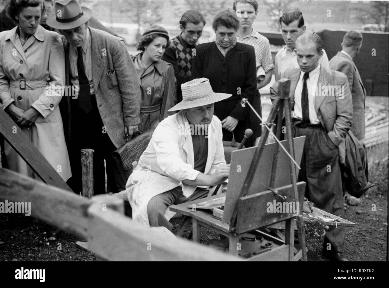 Allemagne - Deutschland ca. 1950, Passanten schauen einem Künstler à Essen beim Malen über die Schulter. Passants regardant un peintre à son travail. Banque D'Images