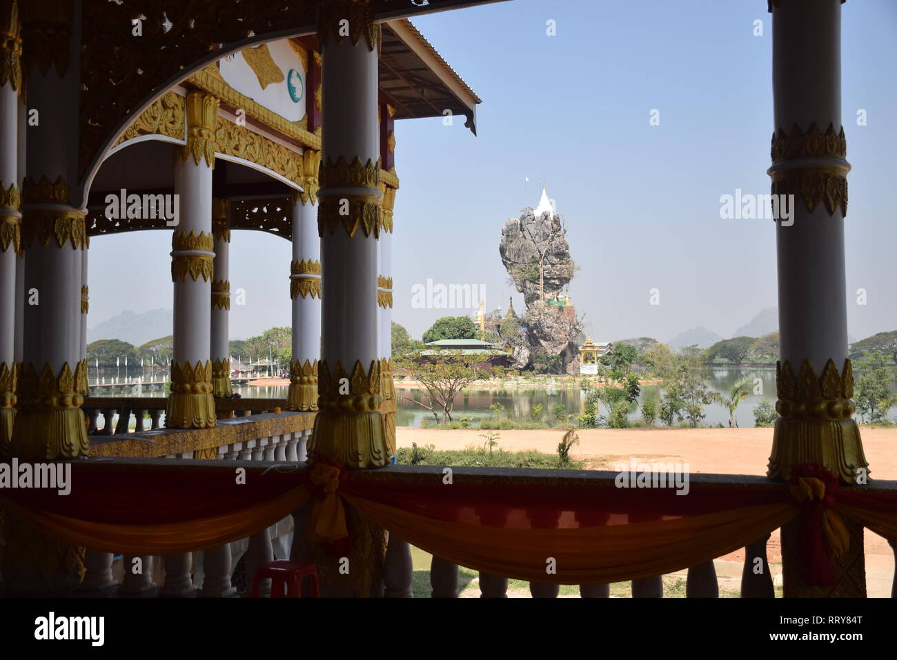 Les colonnes d'or bien décorées dans un temple bouddhiste avec la pagode de Kyauk Ka Lat sur l'arrière-plan en Hpa An, Myanmar Banque D'Images