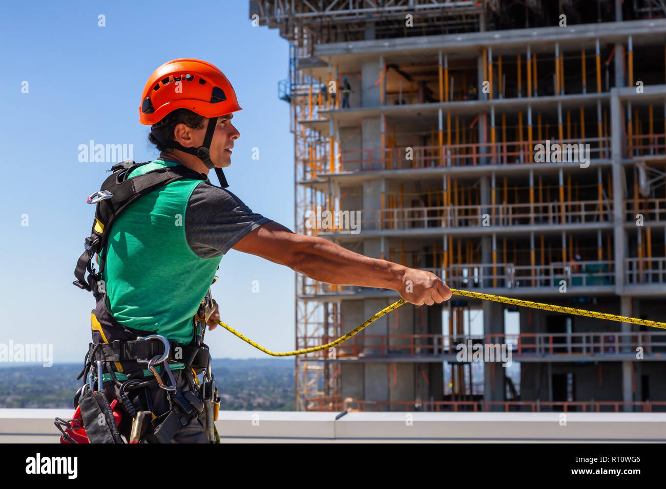 Corde de grande hauteur nettoyant vitre technicien travaille sur un chantier de construction au cours d'une journée ensoleillée. Prises à Burnaby, Vancouver, Colombie-Britannique, Canada. Banque D'Images