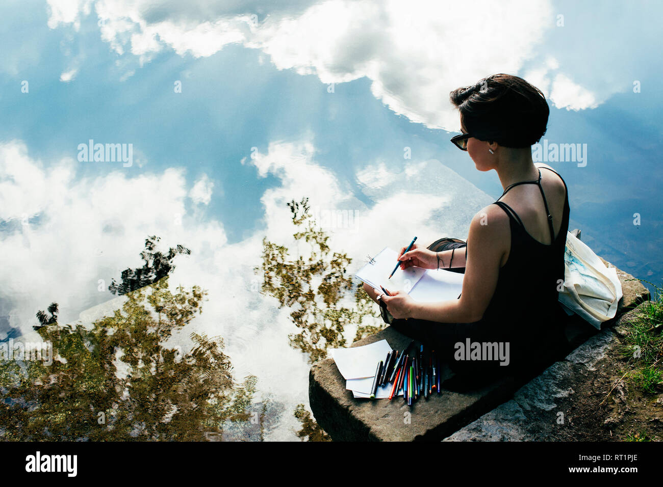 Vue arrière d'un artiste assis sur un banc près de l'eau dimensions Banque D'Images