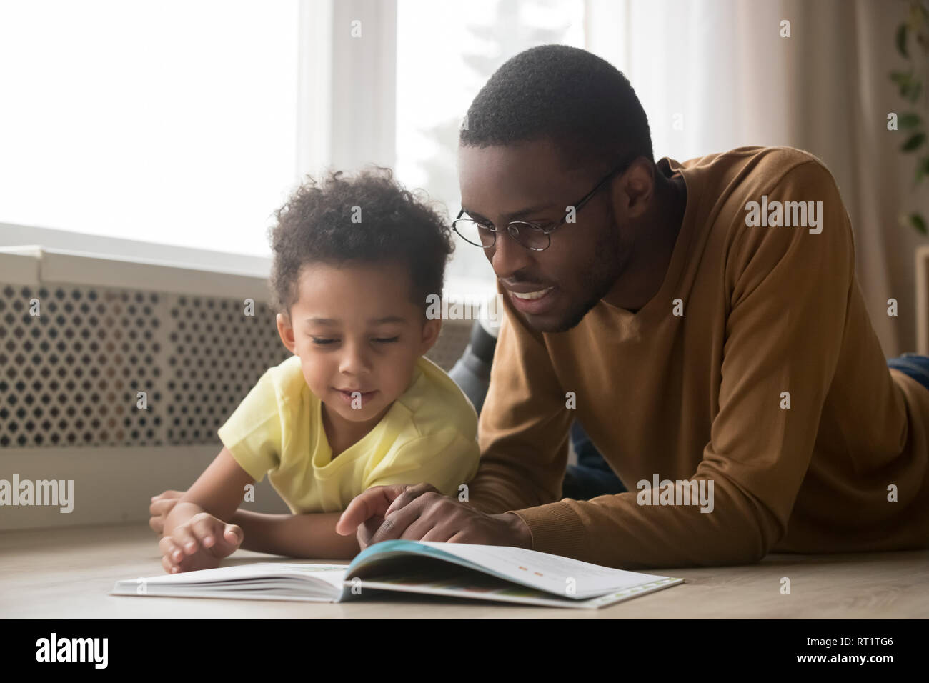 Heureux père noir et petit garçon livre de lecture à la maison Banque D'Images