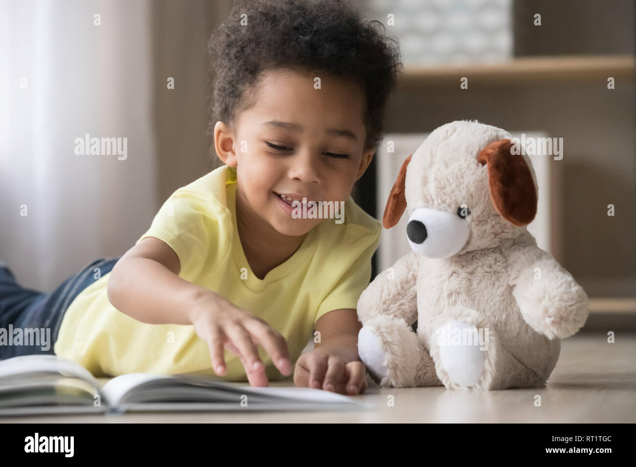 L'Afrique de l'heureux petit garçon jouer seul lecture livre à toy Banque D'Images