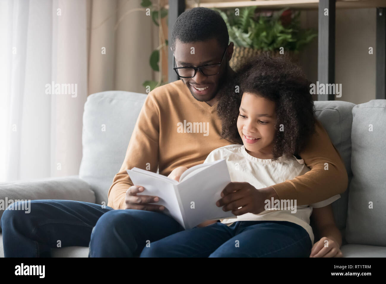 Famille heureuse père et fille enfant noir lecture livre histoire Banque D'Images