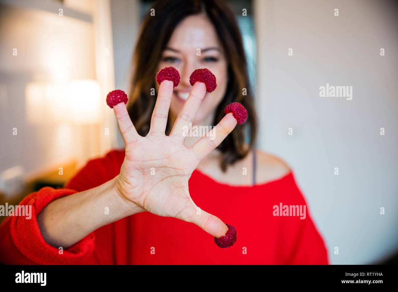 Woman , cuisine avec rasperries sur ses doigts Banque D'Images