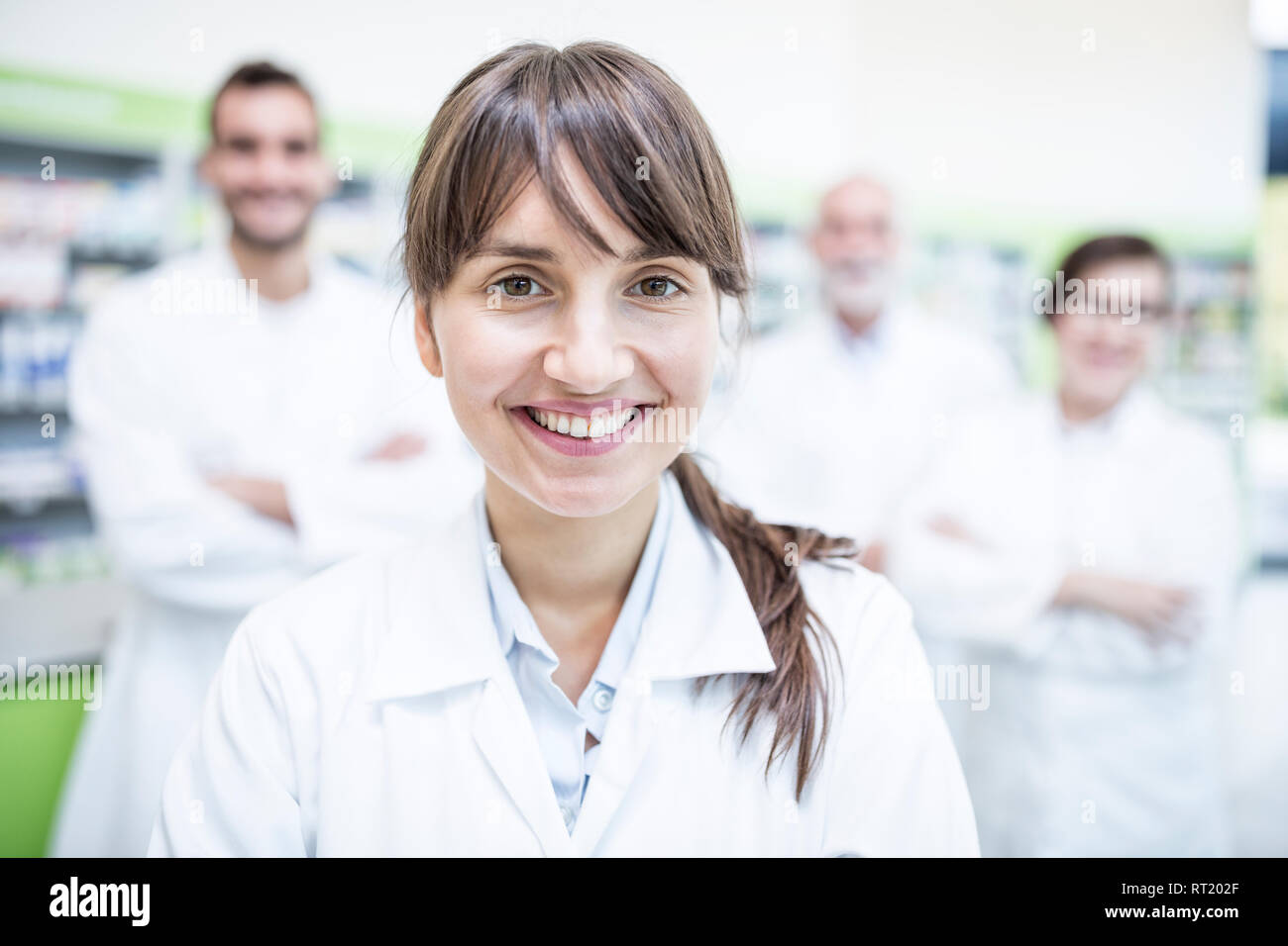 Portrait of smiling docteur en pharmacie avec des collègues en arrière-plan Banque D'Images