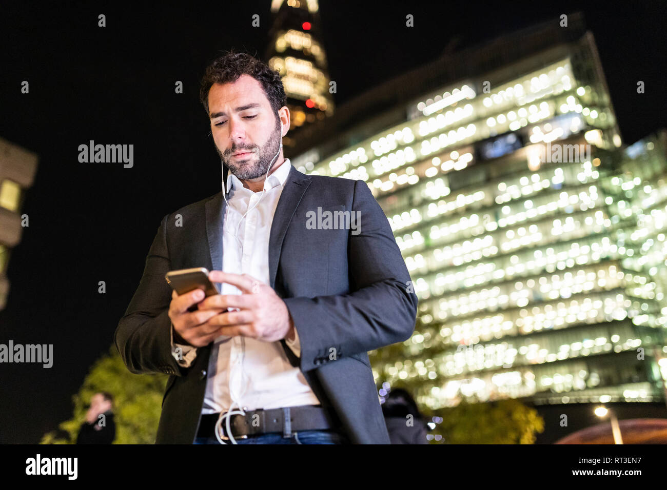 UK, Londres, homme d'affaires sur l'aller vérifier son téléphone lors des trajets de nuit Banque D'Images