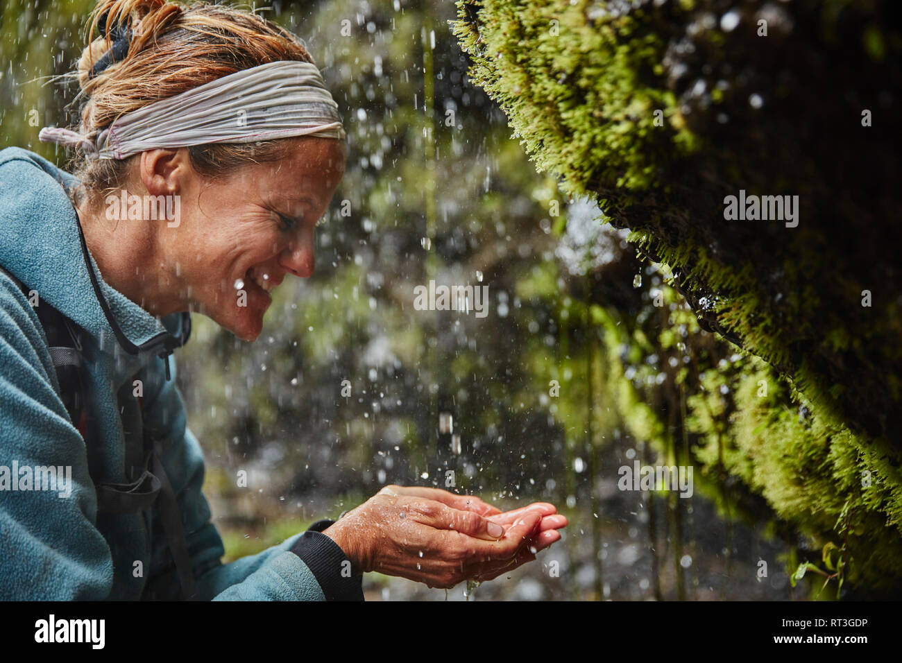 Le Chili, la Patagonie, volcan Osorno, femme avec de l'eau rafraîchissante de Las Cascadas waterfall Banque D'Images