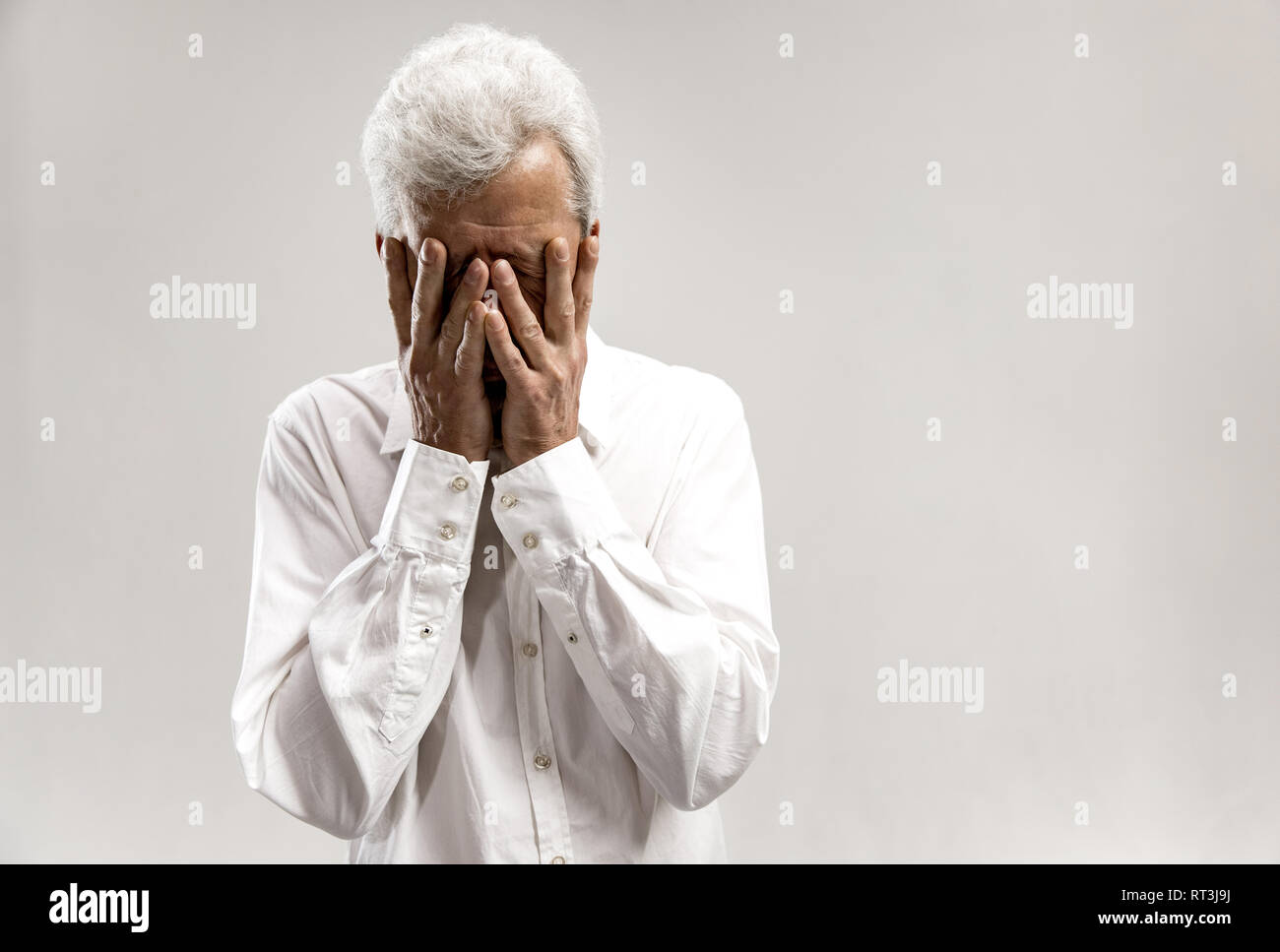 Portrait de vieil homme en colère qui couvre le visage en pleurs. Isolé sur fond gris Banque D'Images