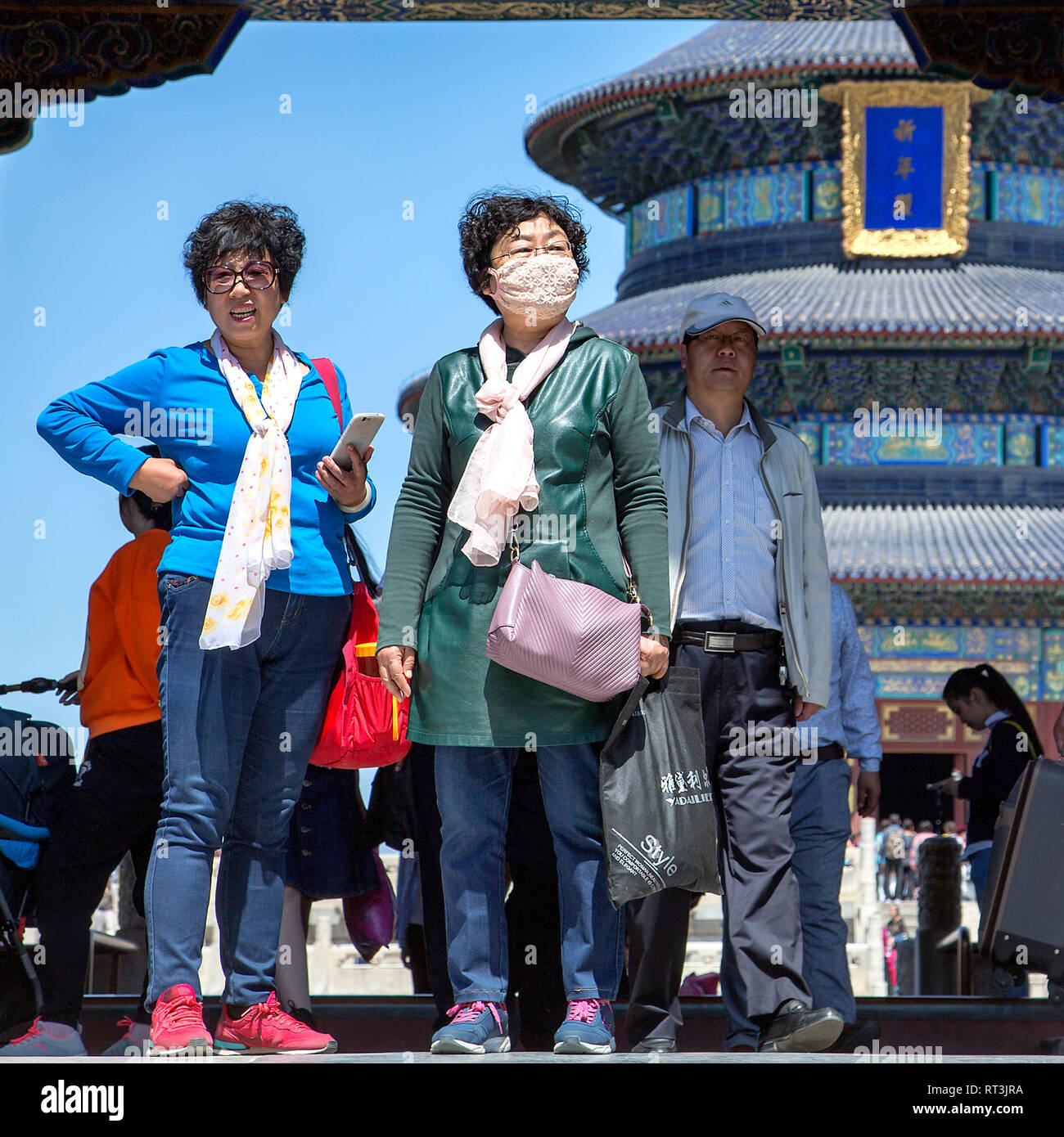 Deux touristes de sexe féminin dans le peuplement complexe du Temple du Ciel, l'un porte un masque de la pollution. Derrière eux la salle de prière pour les bonnes récoltes peuvent être vus. Banque D'Images