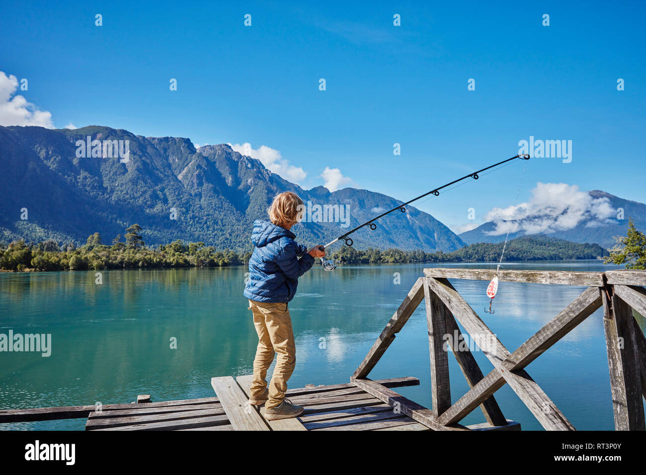 Chili, Lago Rosselot, Chaiten, boy standing on jetty la pêche dans le lac Banque D'Images
