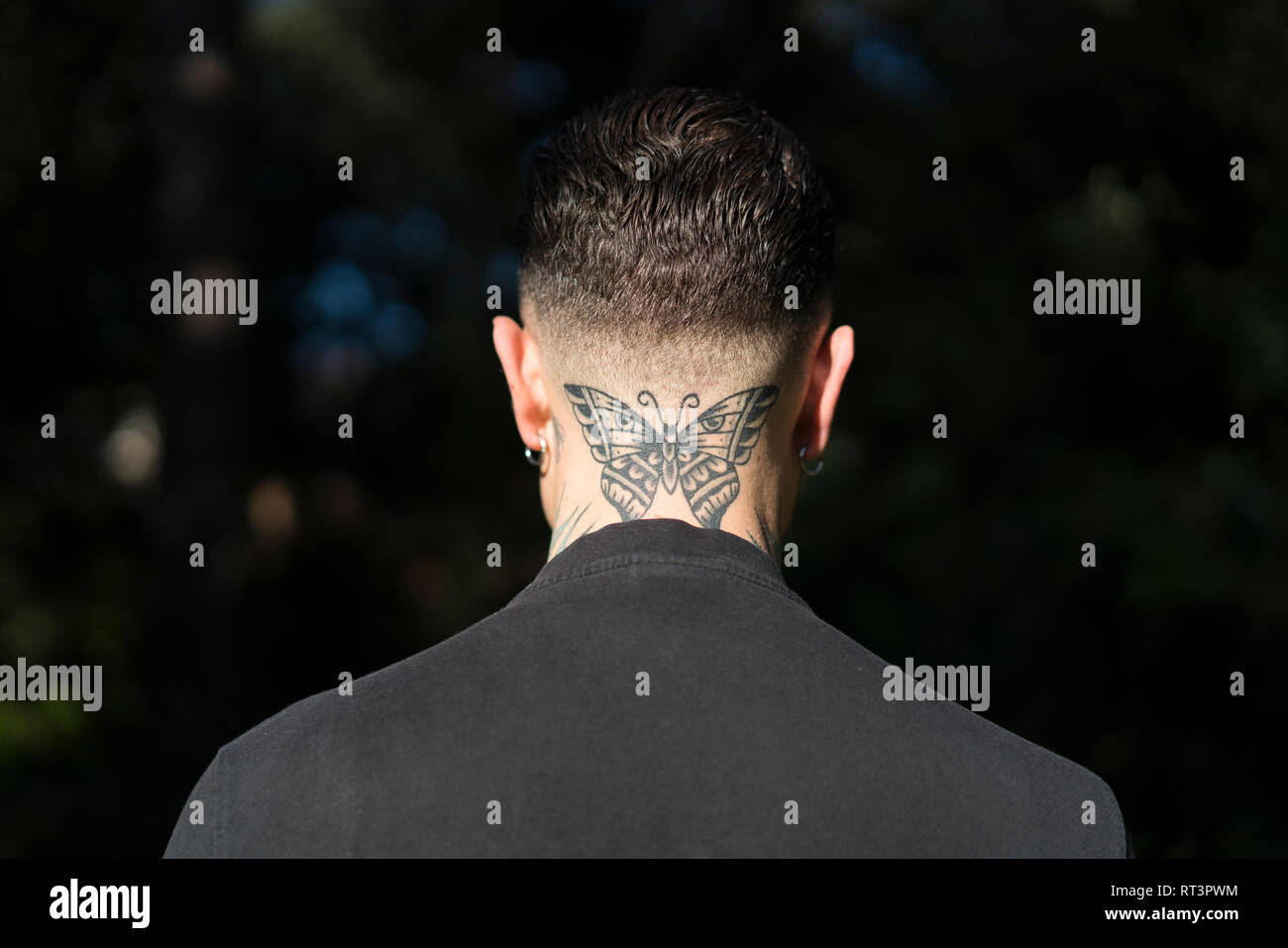 Vue arrière de l'homme avec papillon tatoué sur son cou Banque D'Images