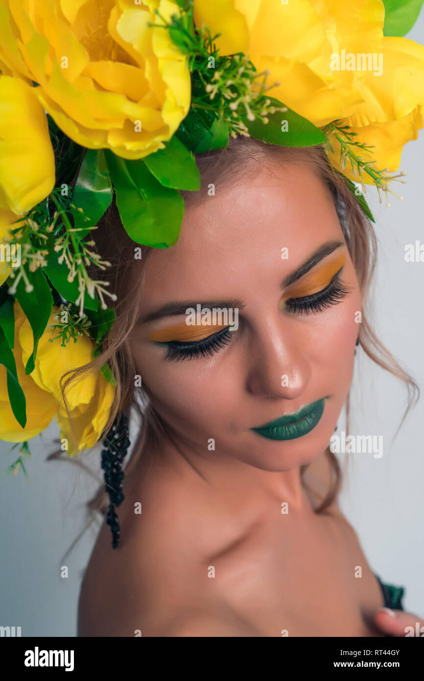 Close-up face à une belle jeune fille avec un miroir lumineux et de grandes fleurs jaunes sur la tête. Banque D'Images