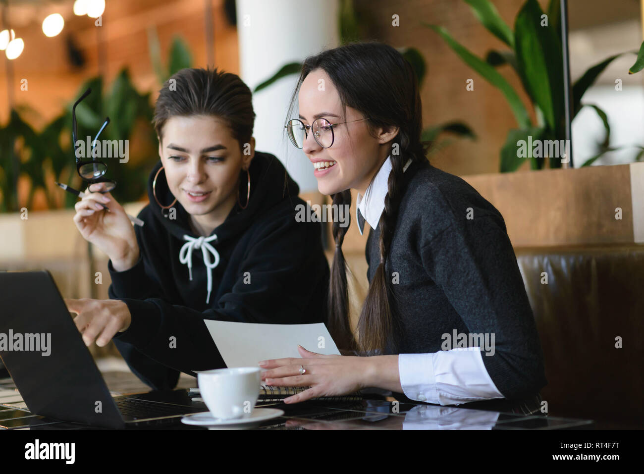 Cheerful étudiantes ayant coopéré positivement sur faire leurs devoirs ensemble Banque D'Images