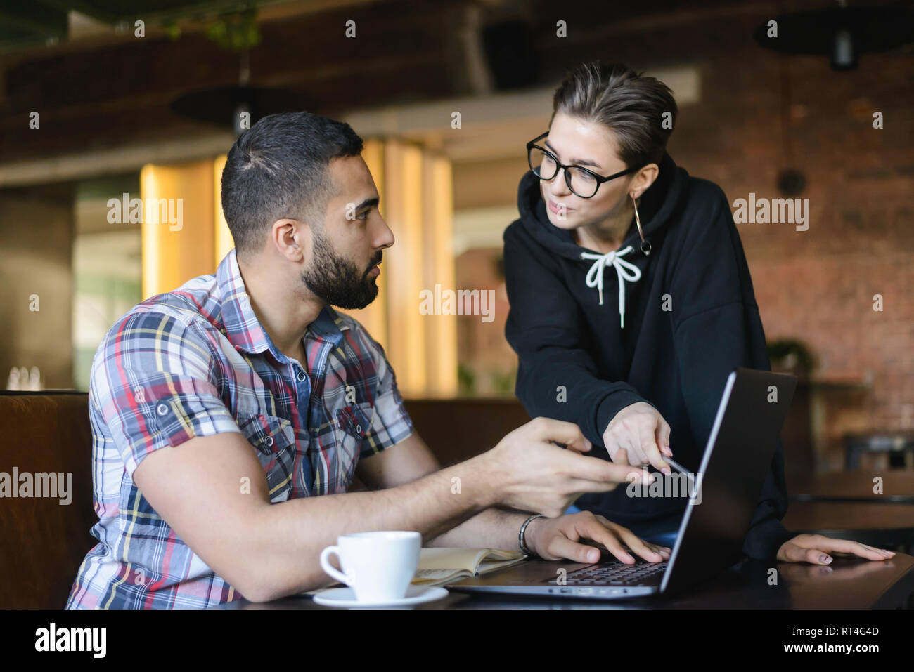 Deux camarades intelligente à faire leurs devoirs avec l'ordinateur portable à l'intérieur cafe Banque D'Images