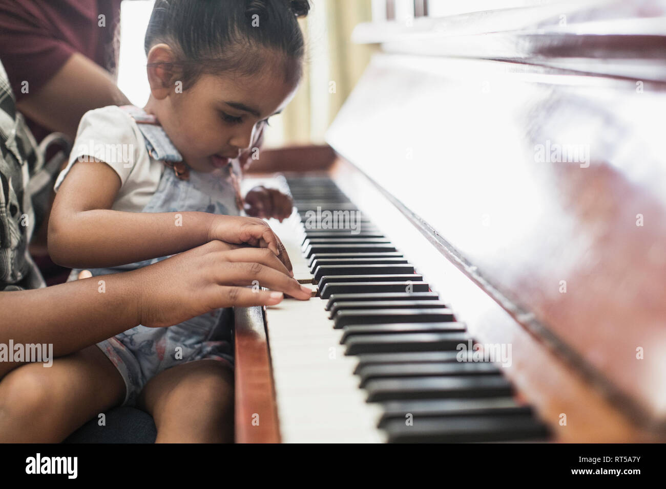 Curieux girl playing piano Banque D'Images