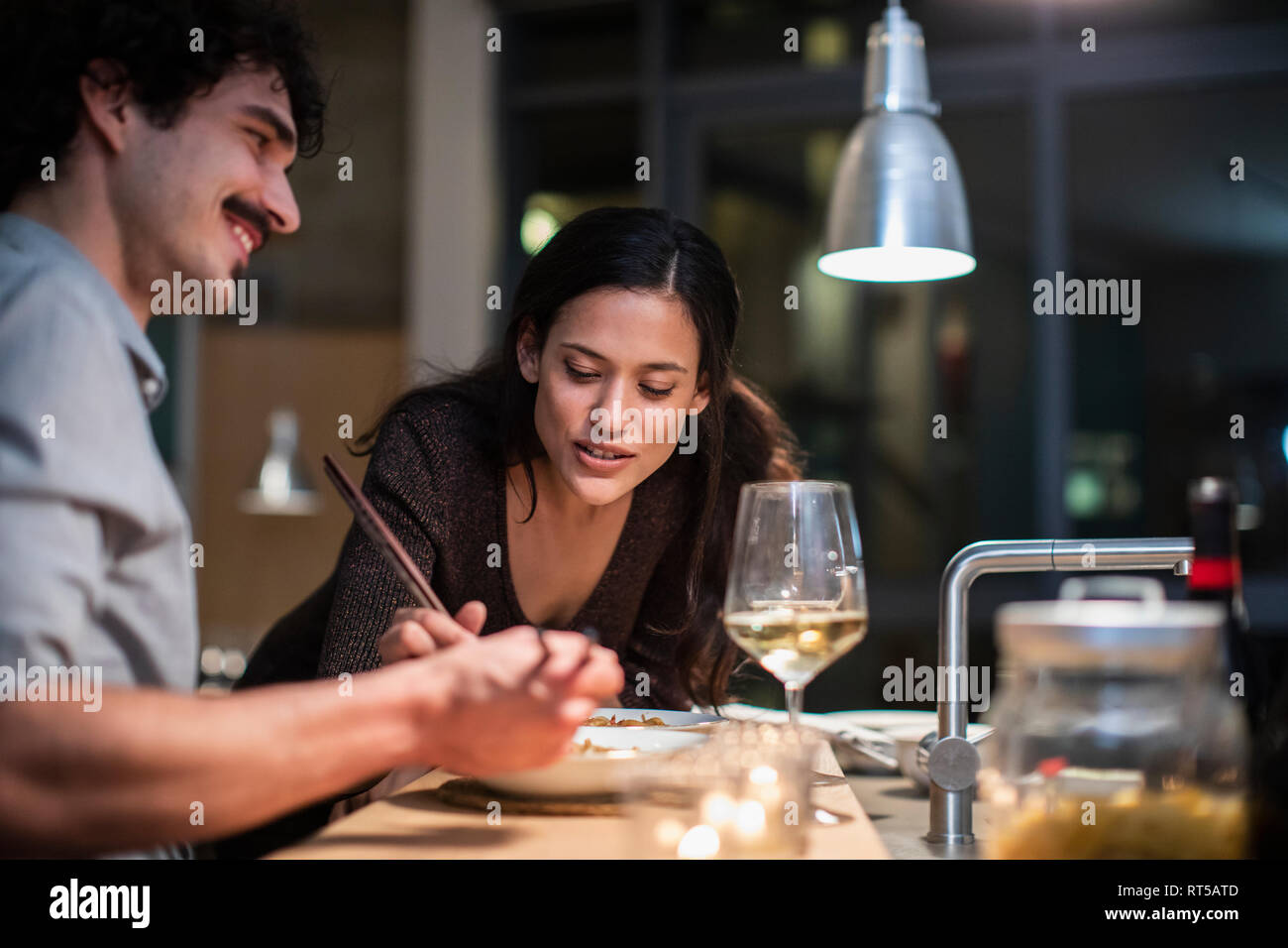 Couple eating dinner avec des baguettes et de boire le vin blanc dans la cuisine de l'appartement Banque D'Images