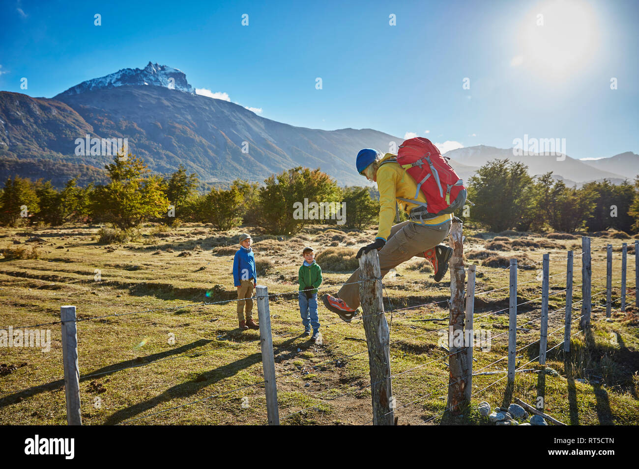 Le Chili, Cerro Castillo, mère de deux fils en randonnée saute au-dessus de clôture Banque D'Images