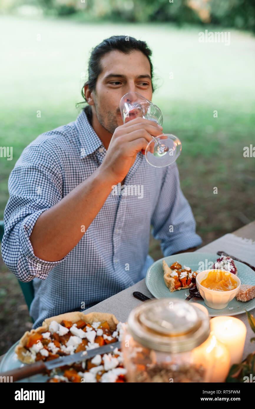 L'homme de boire un verre de vin à table de jardin Banque D'Images