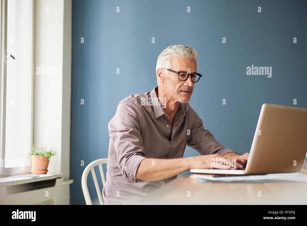 Mature man using laptop sur la table à la maison Banque D'Images