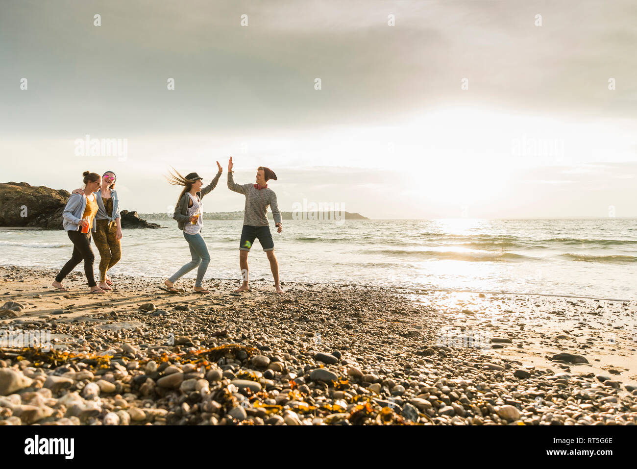 Heureux amis marchant sur la plage au coucher du soleil Banque D'Images