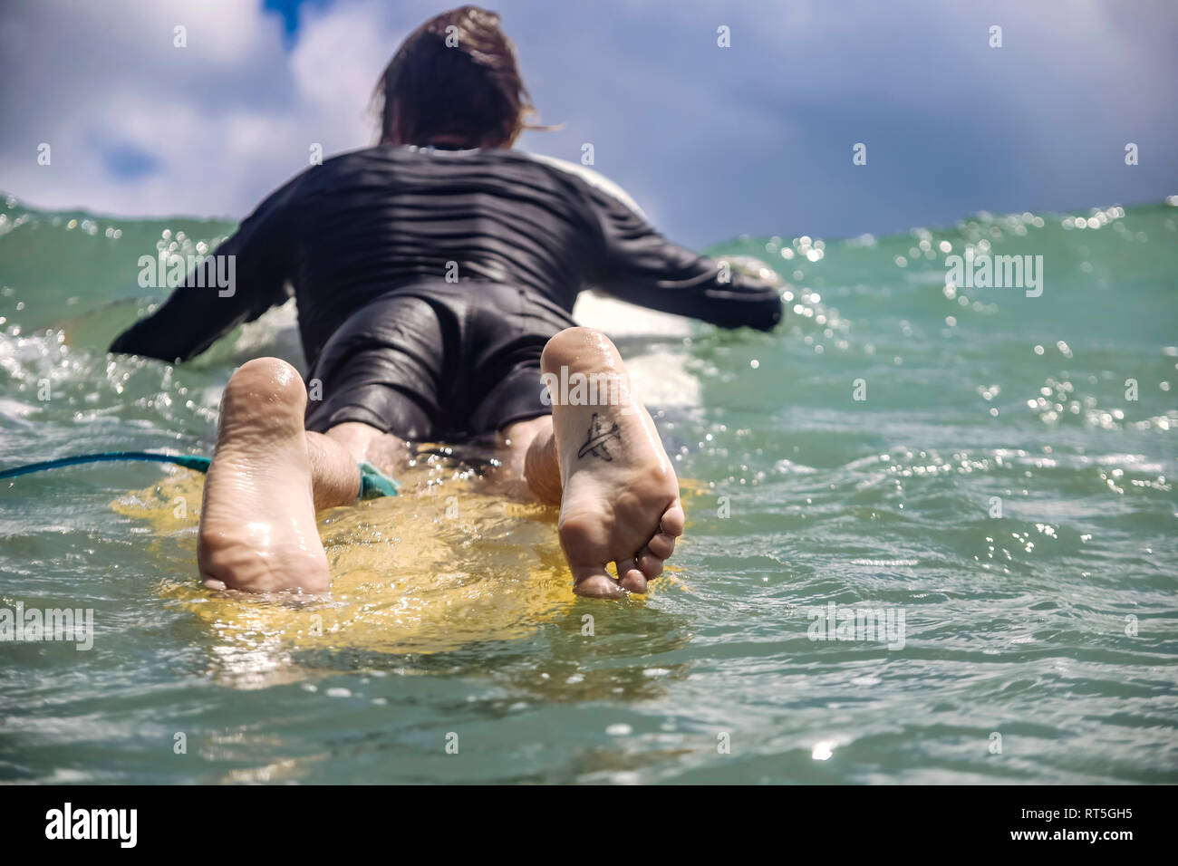 L'INDONÉSIE, Bali, Kuta, surfer allongé sur une planche de surf, tatouage sur la plante des pieds Banque D'Images