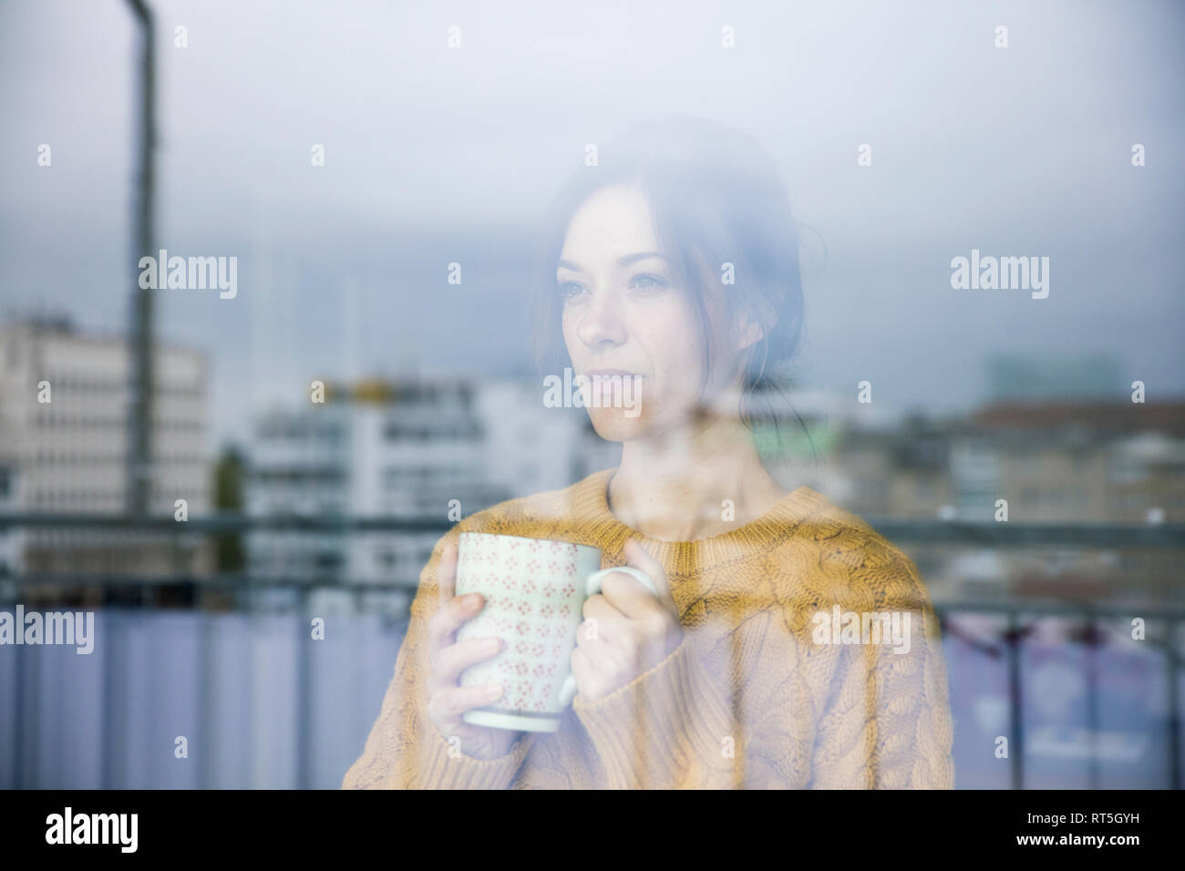 Femme triste debout à la fenêtre, de boire du thé Banque D'Images Femme triste debout à la fenêtre, de boire du thé Banque D'Images