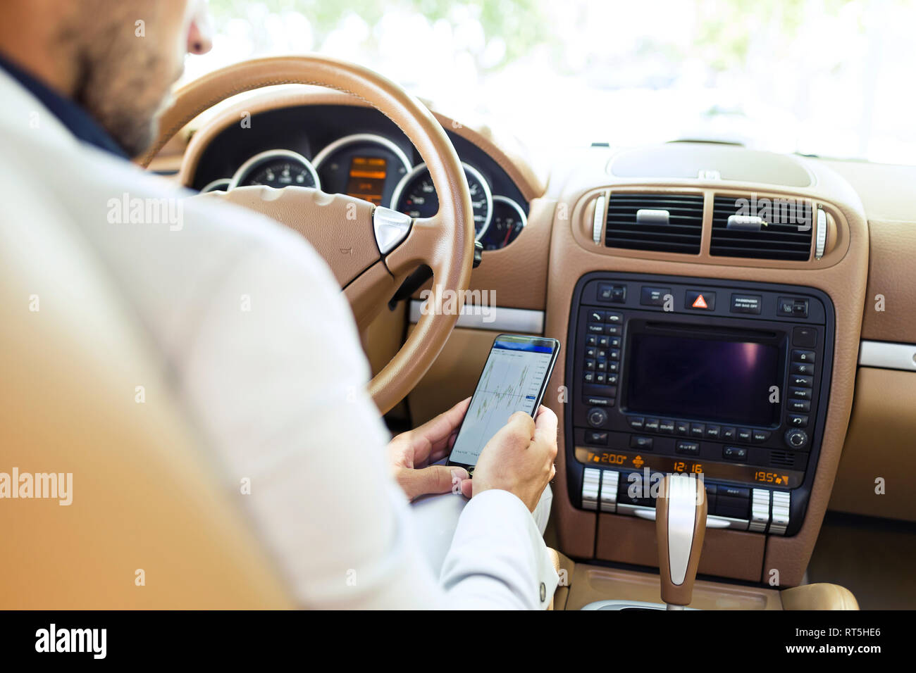 Young businessman sitting in car, using smartphone Banque D'Images
