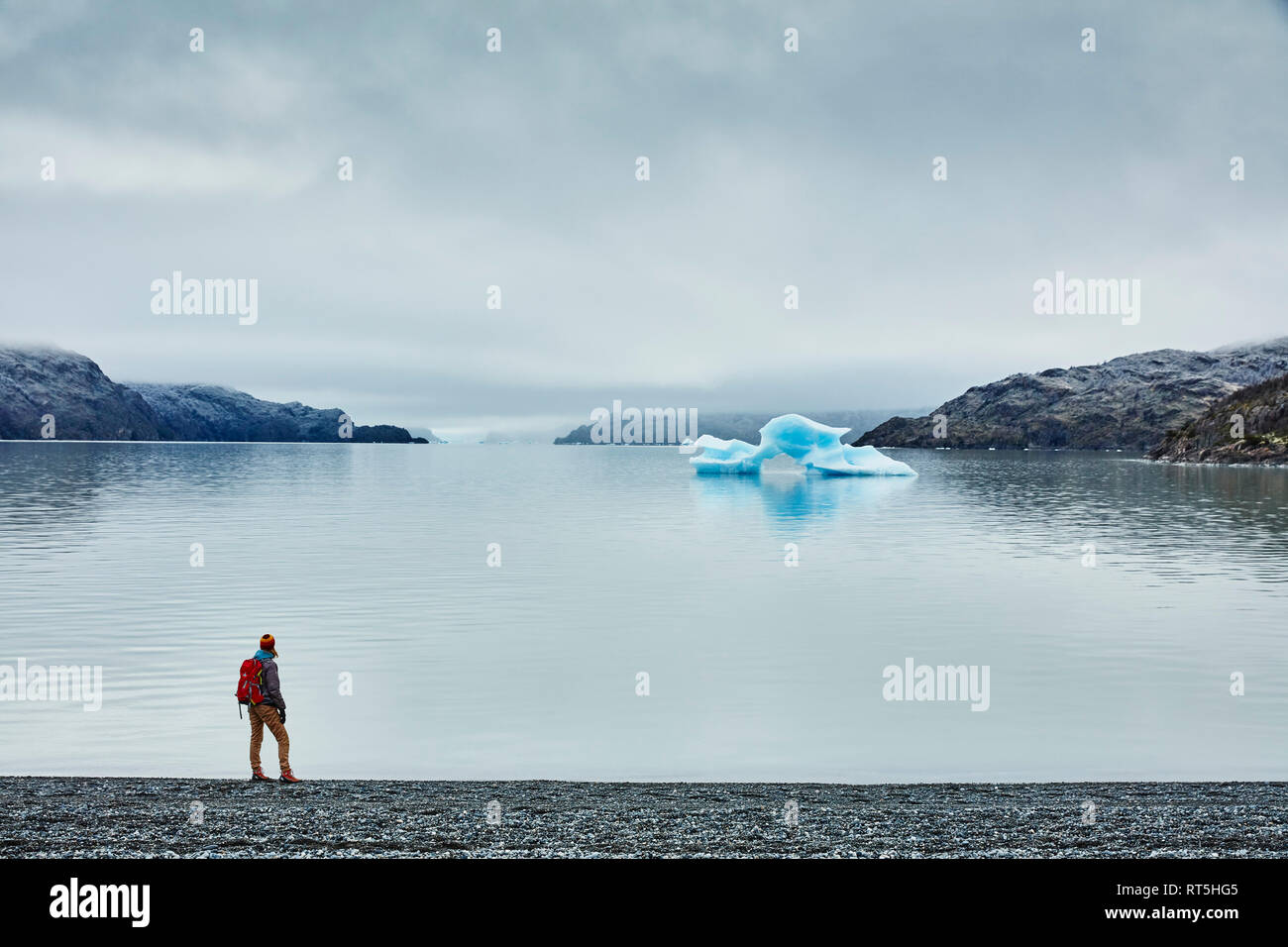 Le Chili, le parc national Torres del Paine, Lago Grey, femme debout sur la rive à la recherche à l'iceberg Banque D'Images