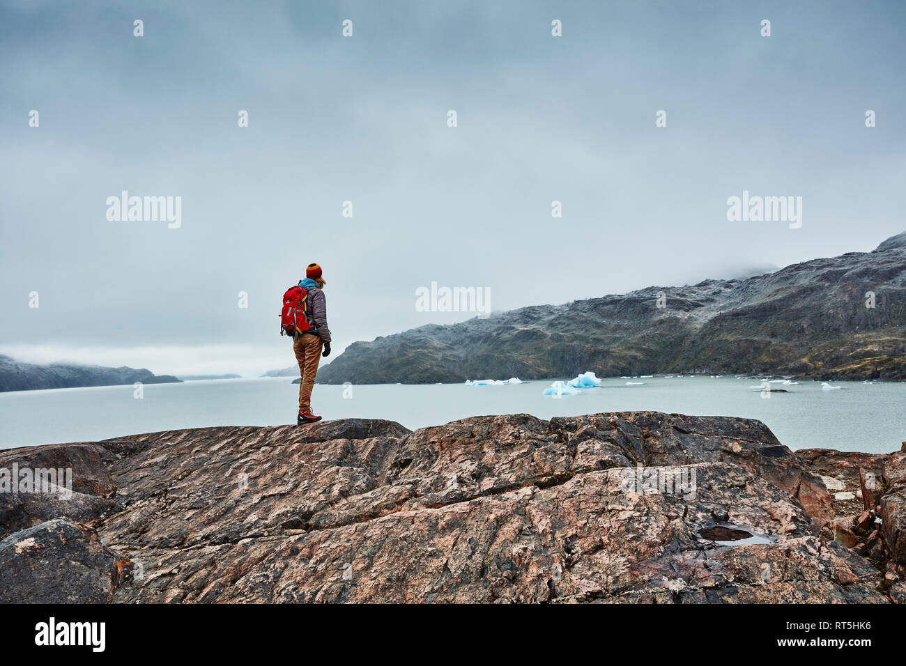 Le Chili, le parc national Torres del Paine, Lago Grey, femme debout sur la roche à la rive à la recherche à l'iceberg Banque D'Images