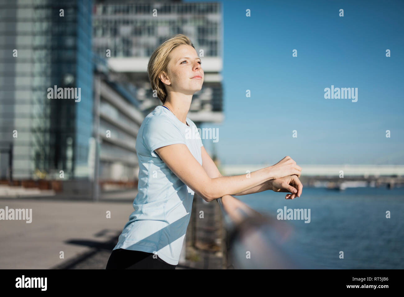 Jeune femme debout au bord du fleuve, en profitant du soleil Banque D'Images Jeune femme debout au bord du fleuve, en profitant du soleil Banque D'Images