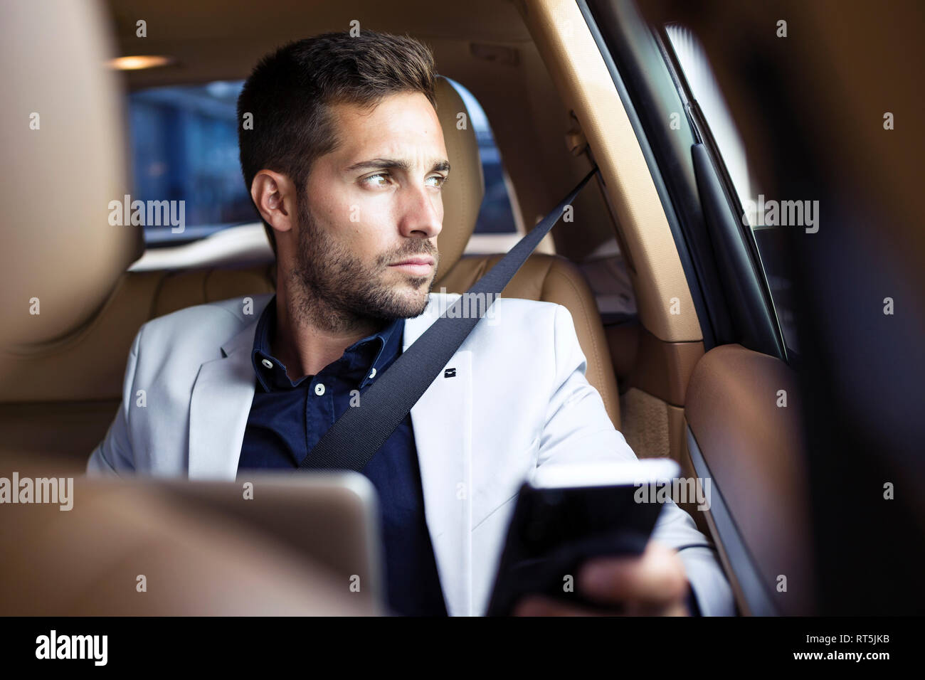 Young businessman sitting in car, using smartphone Banque D'Images