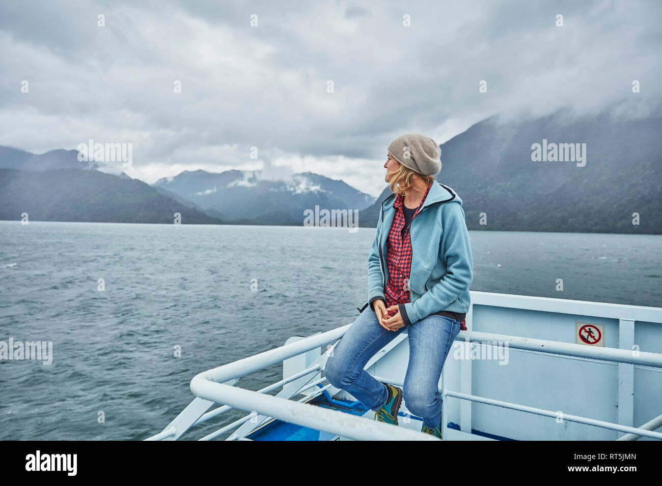 Le Chili, l'Hornopiren, femme assise sur le rail d'un traversier à chez fjord Banque D'Images