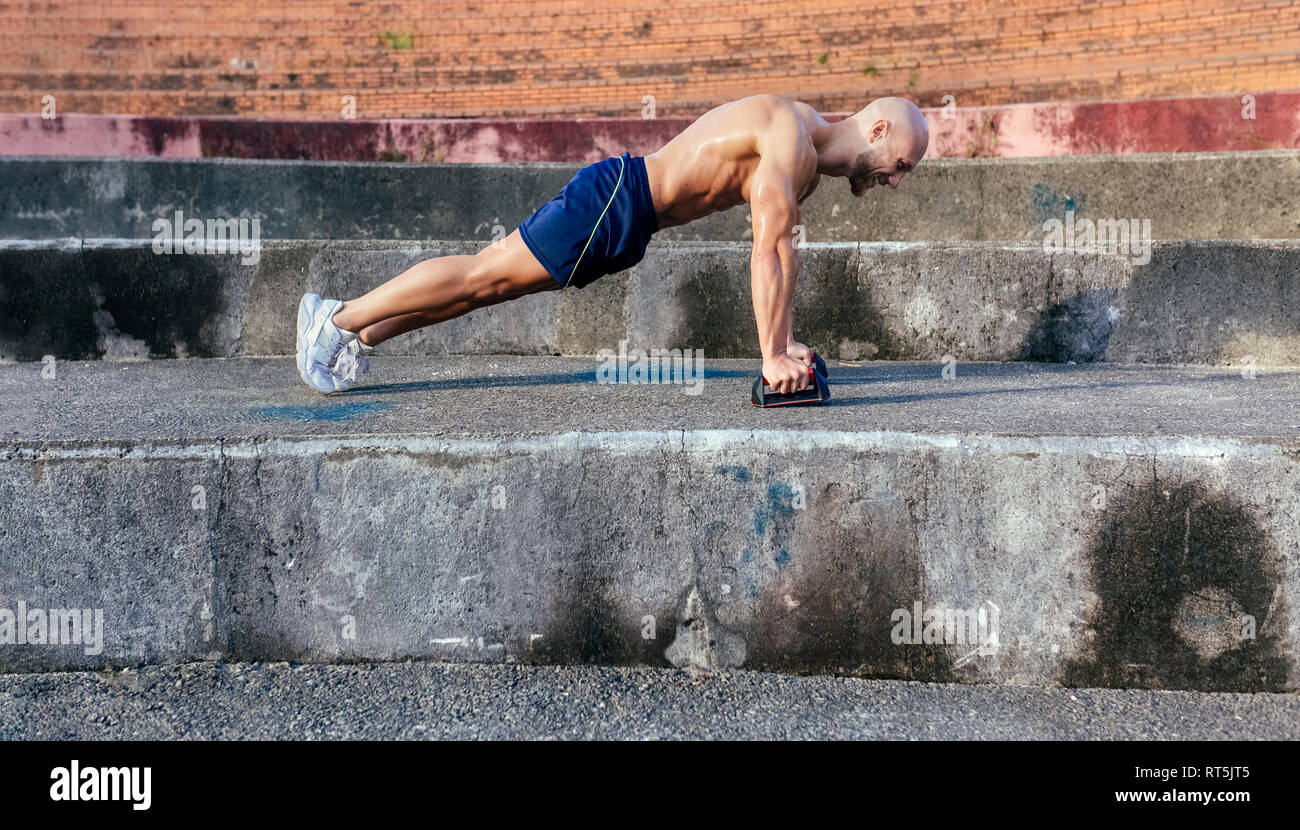 Homme musclé torse nu faisant push-ups à l'extérieur Banque D'Images