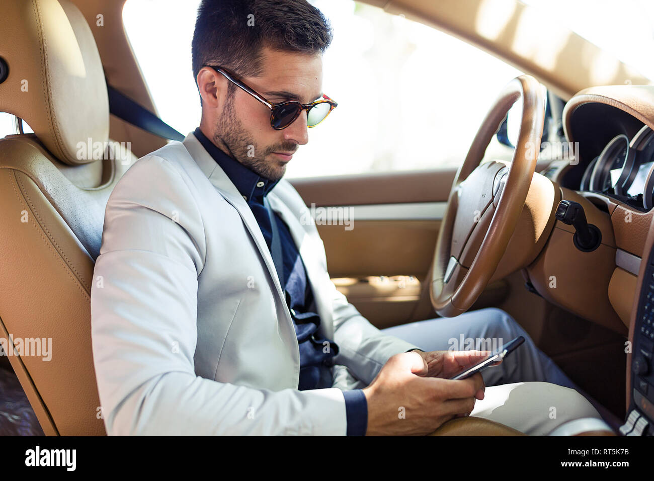 Young businessman sitting in car, using smartphone Banque D'Images
