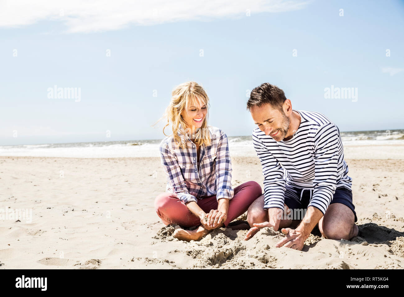 Heureux couple assis sur la plage Banque D'Images