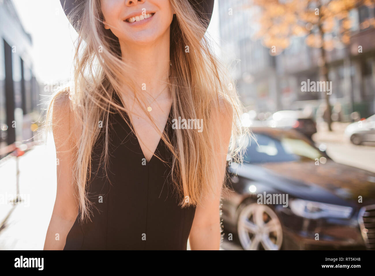 Rire femme blonde vêtue de noir marcher dans la ville, vue partielle Banque D'Images
