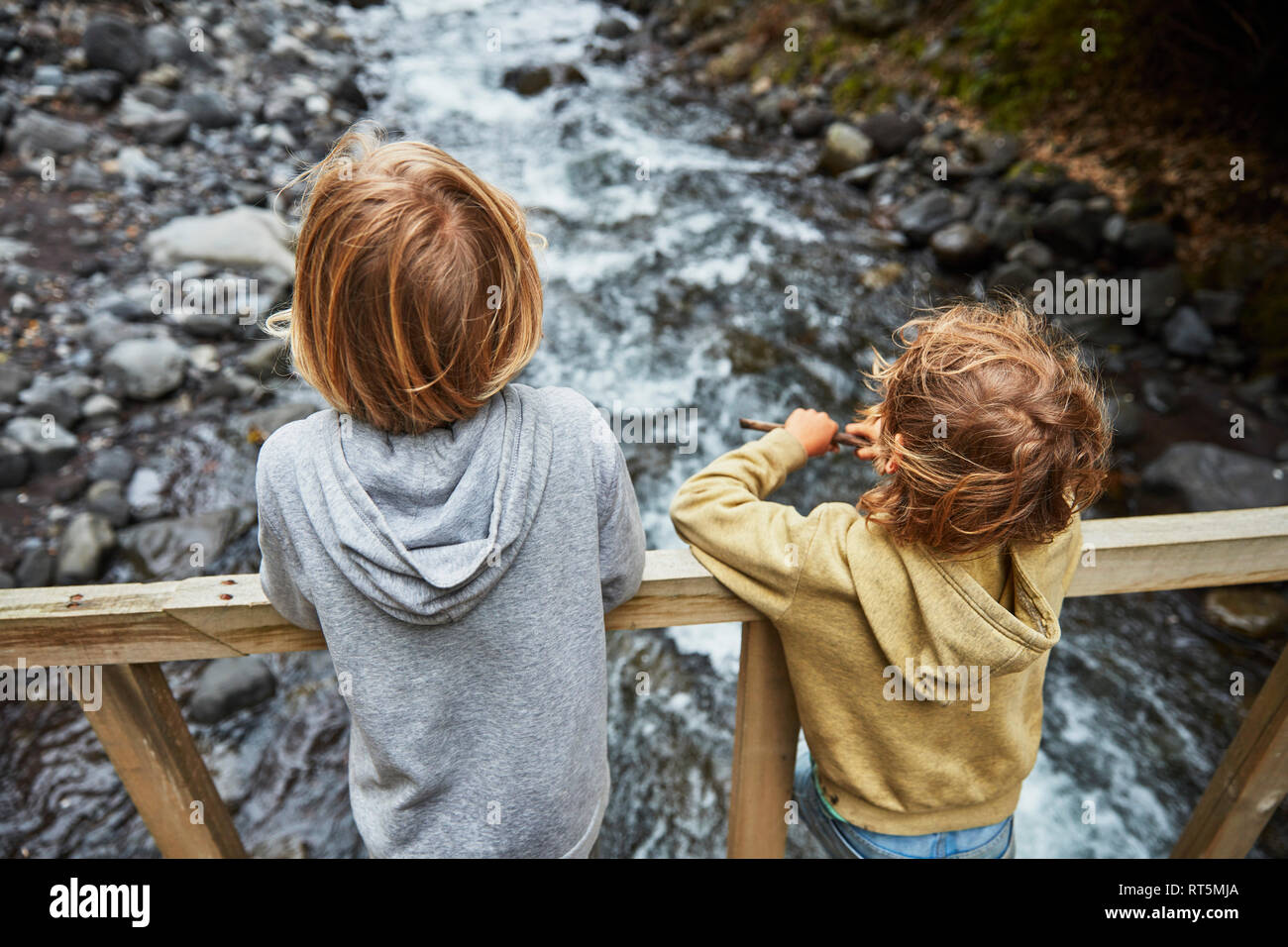 Le Chili, la Patagonie, volcan Osorno, Las Cascadas cascade, deux garçons debout sur pont au dessus d'une rivière Banque D'Images
