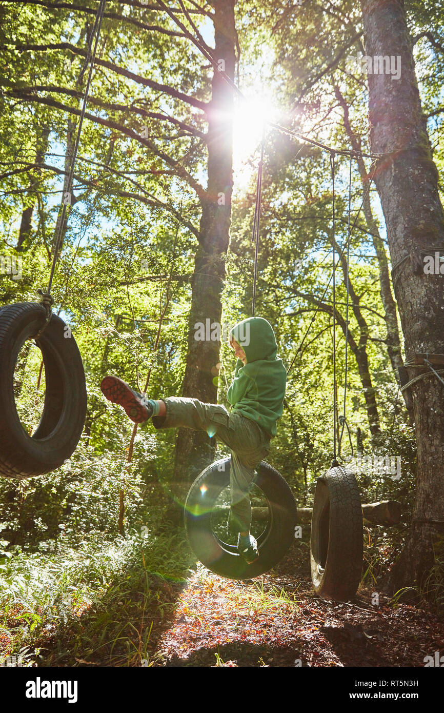 Boy balancing sur pneus à un parc d'aventure en forêt Banque D'Images