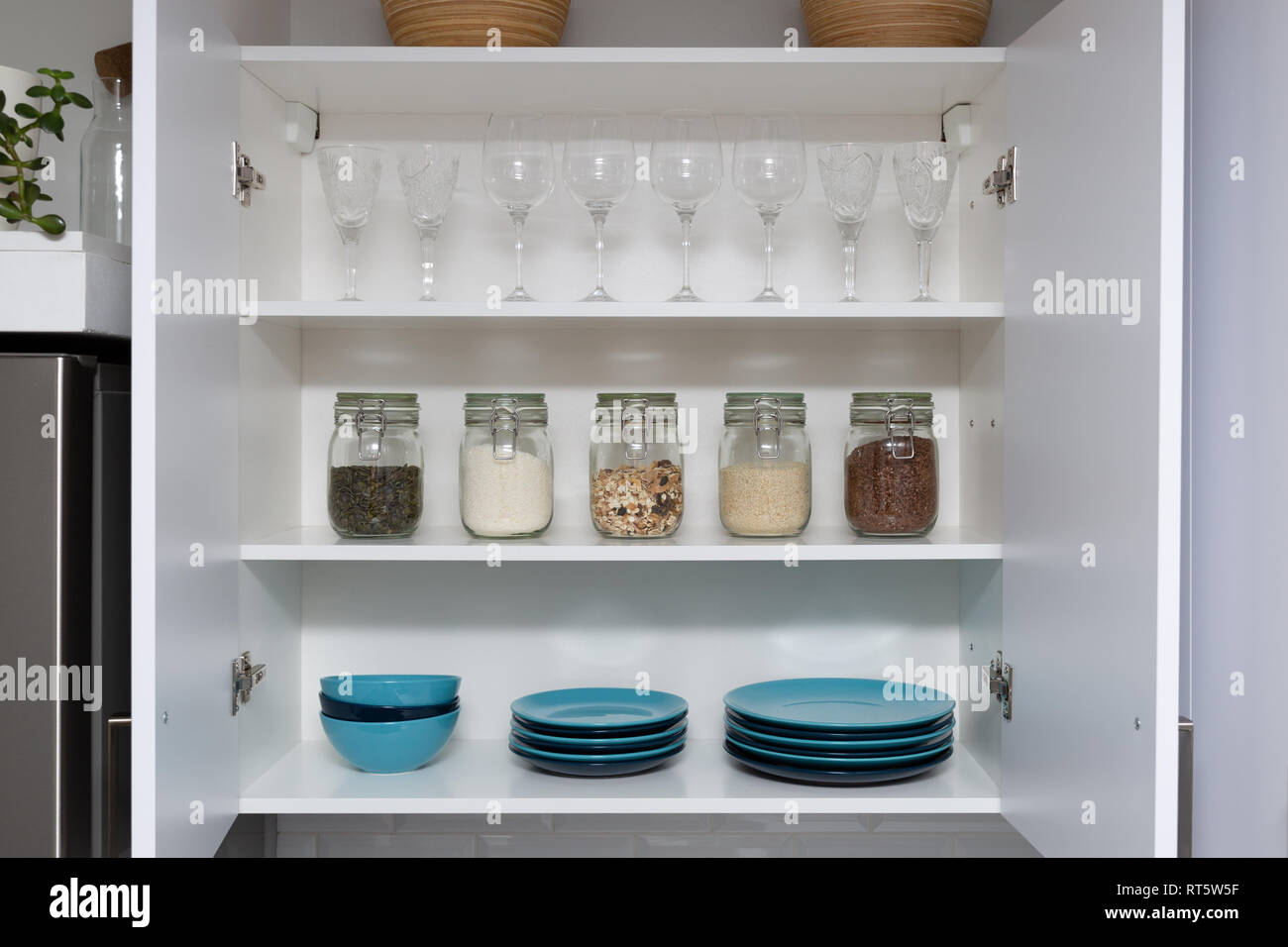 Différentes graines dans des bocaux de stockage en garde-manger, cuisine moderne blanc en arrière-plan. Organisation Smart Kitchen Banque D'Images
