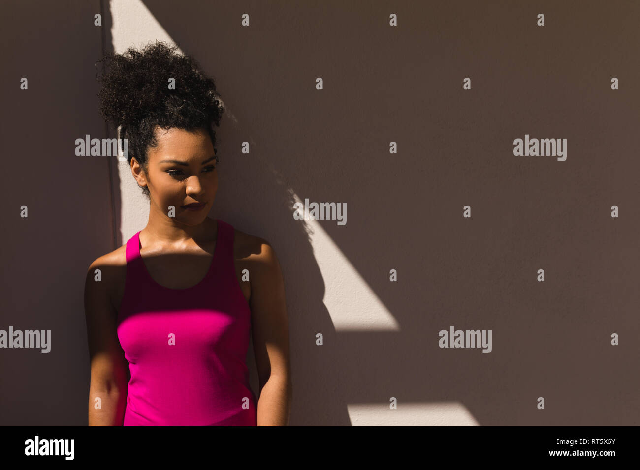Femme debout contre le mur dans l'arrière-cour d'accueil Banque D'Images