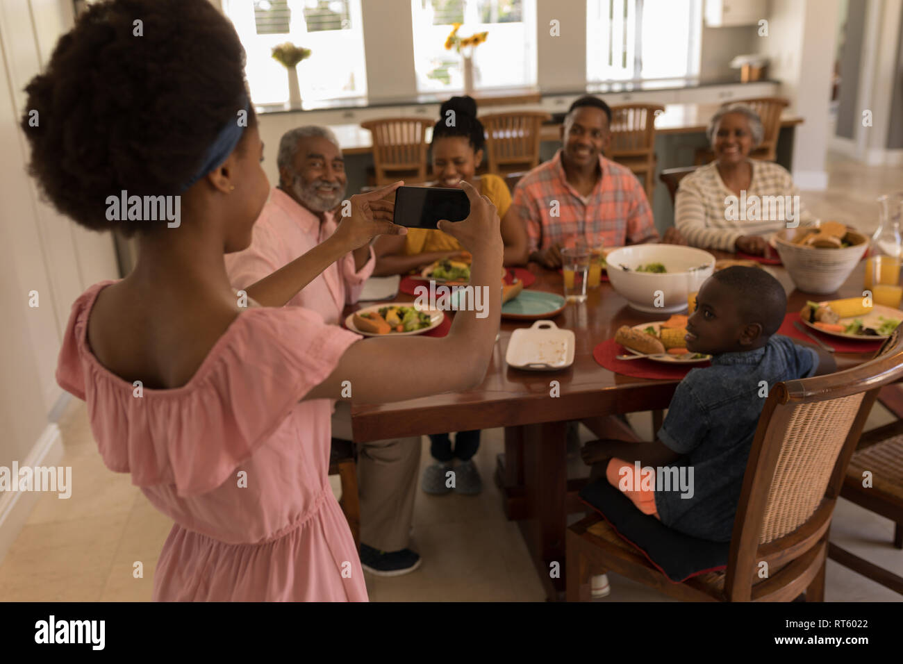 Girl en cliquant sur photos de famille avec le téléphone mobile sur table à manger Banque D'Images