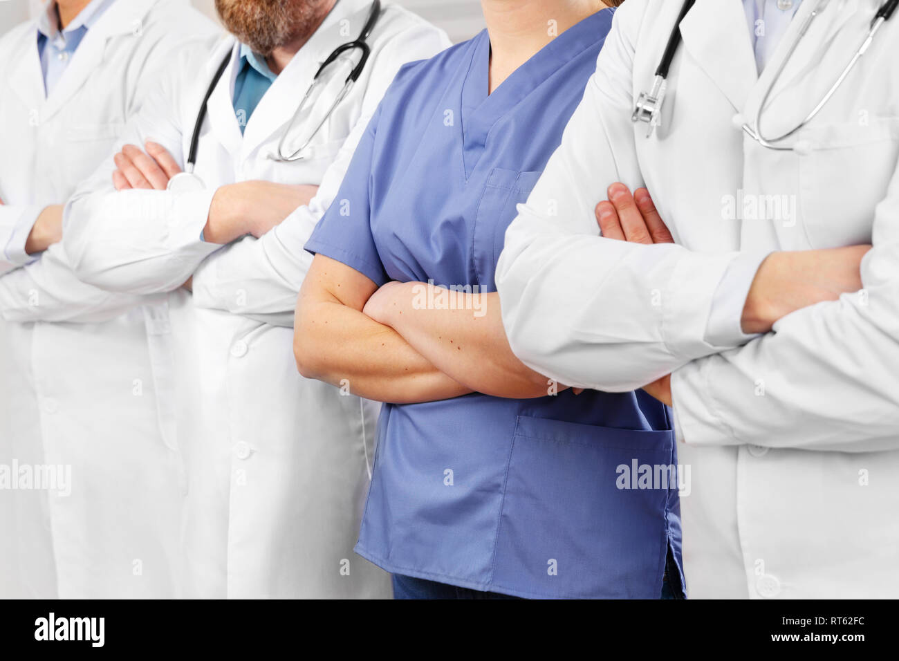 Les médecins et les infirmiers dans l'équipe de soins de santé avec les bras croisés dans une rangée à l'hôpital Banque D'Images