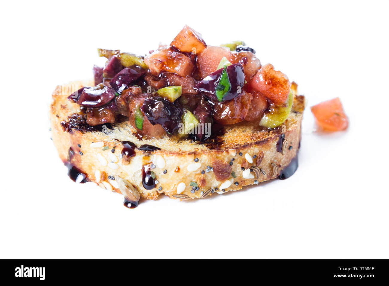 Bruschetta fraîche faite avec une variété d'olives et tomates grillées dés sur de petites tranches de pain arrosé d'une réduction balsamique isolé sur une brindille Banque D'Images